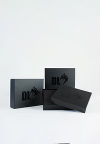 Des boîtes en carton noir avec une finition mate, arborant un logo avec un motif de cheval et les lettres "DL". Différentes tailles présentées.