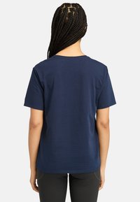 Navy sininen puuvillapaita, lyhyet hihat, sileä kangas, pyöreä kaula-aukko ja rento malli, esitetty takaa. Minimalistinen muotoilu ilman kuvioita.