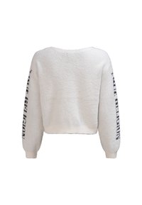 Weißer, kurz geschnittener Pullover mit flauschiger Textur, weiten Ärmeln und schwarzem Logoaufdruck entlang des linken Ärmels. Keine sichtbaren Verschlüsse.