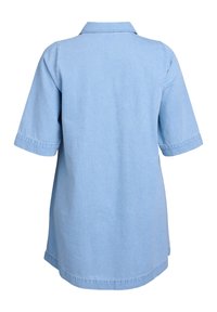 Šviesiai mėlynas džinsinis marškinėliai su trumpomis rankovėmis, smailiu apykakle ir tiesiu kirpimu. Jame matomi siūlės ir šiek tiek suapvalintas kraštas.