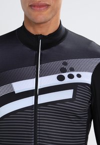 Černý cyklistický dres s předním zipem, který má geometrický vzor v odstínech šedé a bílé, vyrobený z hladkého, elastického materiálu.