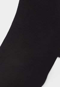 Κοντινή λήψη μαύρου σουέντ μποτάκι αστραγάλου με μυτερή μύτη σε λευκό φόντο.