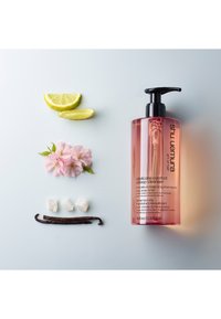 Plastpumpflaska i rosa gradient; etiketten lyder "delicate comfort deep cleanser." Följd av citronskivor, körsbärsblommor, vaniljstång och kristaller.