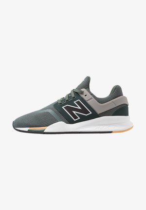 Zapatilla deportiva New Balance en gris y verde oscuro con parte superior de malla, diseño con cordones, entresuela blanca y suela exterior de goma en color marrón claro y negro.