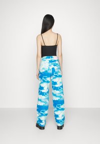 Siniset housut, joissa on pilvimuotti sydänkuvioilla, yhdistettyinä mustaan, tiukkaan yläosaan. Housuissa on löysä, leveälahkeinen malli.