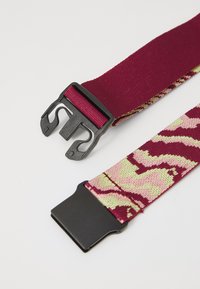 Adjustable fabric belt in maroon with a pink and green camouflage pattern. Features two black plastic buckle clasps for secure fastening.