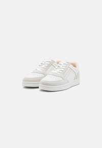 Sneakers bianchi caratterizzati da un mix di pelle liscia e camoscio, con dettagli perforati, punta arrotondata e suole in gomma. Accenti di colore chiaro visibili.