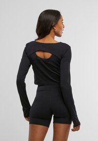 Musts mustriga must särk avatud tagumise lõikega, millele on sobitatud mustad lühikesed püksid. Sile tekstuur ja keha kallistav disain.