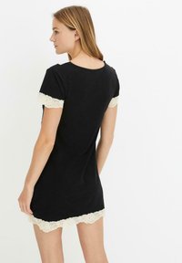 Abito corto nero con accenti in pizzo sulle maniche e sull'orlo, caratterizzato da un colletto rotondo e una texture morbida e liscia.