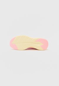 Suela de zapatilla con una base amarilla, que presenta acentos rosas. Superficie texturizada con surcos distintivos y un diseño aerodinámico.