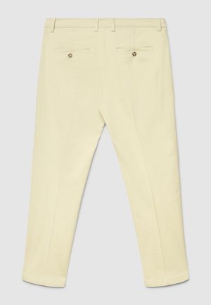 Pantaloni giallo chiaro con vestibilità sagomata, dotati di due tasche posteriori, una texture liscia e dettagli di cuciture sottili.