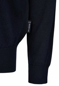 Navy gebreide trui met ribbels bij de cuffs, voorzien van een klein label met de tekst "HECHTER" in rood en wit. Vriendelijke textuur.