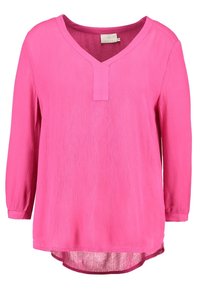 Blusa a maniche lunghe di un vivace colore rosa, con scollatura a V e tessuto texture, caratterizzata da un orlo posteriore leggermente più lungo e un piccolo dettaglio colletto nella parte frontale.