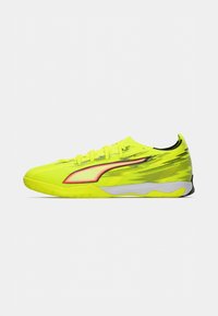 Neon-gelber Sportschuh mit schlankem Design, ausgestattet mit einer strukturierten Oberseite, Schnürsenkeln und einem kontrastierenden roten Akzent an der Seite.