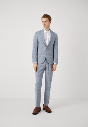 Light blue plaid suit with a fitted jacket, flat front trousers, and white dress shirt. Features a notched lapel, two front pockets, and brown shoes.