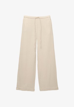 Široké nohavice z jemného béžového materiálu, s textúrovaným povrchom, elastickým pásom s šnúrkou a obšitými lemami.