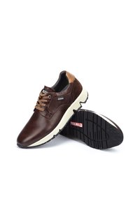 Chaussures en cuir marron avec un talon en suède, un design à lacets, une semelle intermédiaire blanche et une semelle en caoutchouc noir texturé avec des détails de logo de marque.