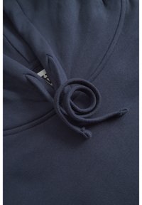 Marineblaue Kapuzenstoff mit strukturierter Oberfläche; verfügt über eine spiralförmig geschlungene Kordel und eine Kapuzenöffnung oben für anpassbaren Sitz.