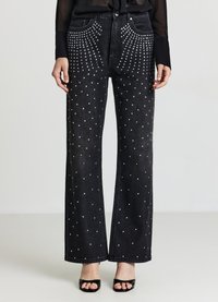 Jeans neri a gamba larga in denim, caratterizzati da un motivo a pois con borchie d'argento sulle tasche anteriori e posteriori. Tessuto liscio.