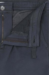 Pantalones color azul marino con una cremallera y un cierre de botón visibles. La tela parece suave y hay un forro texturizado sutil visible en el interior.