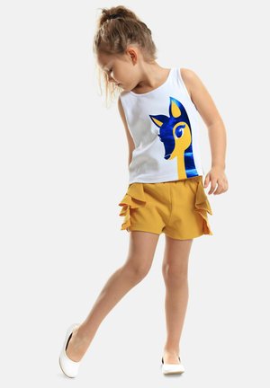 White tank top with a blue and yellow deer graphic; yellow shorts with ruffled accents; white flat shoes; casual summer outfit.