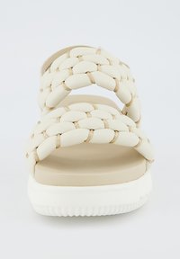 Sandali intrecciati beige con due fasce larghe, caratterizzati da una parte superiore liscia e una suola bianca testurizzata. Design minimalista senza branding visibile.