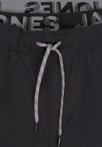 Schwarze Badeshorts mit elastischem Bund, ausgestattet mit einem grauen Kordelzug und gemustertem Innenfutter. Leichter Stoff, glatte Textur.