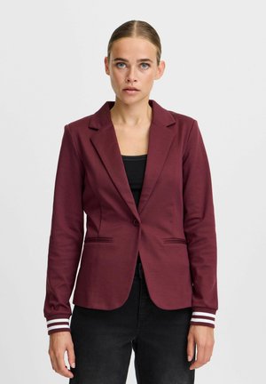 Maroon blazer dengan penutupan satu tombol, dua kantong depan, dan manset bergaris. Kain halus dengan potongan pas dan kerah notch.