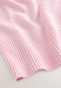 Różowy sweter dzianinowy z pionową prążkowaną fakturą; miękka, gładka powierzchnia; zaokrąglony detal na krawędzi; lekki i elastyczny materiał.