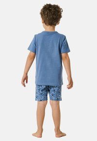 Camiseta de algodón azul con mangas cortas y pantalones cortos azules con un patrón abstracto blanco, vista desde atrás, descalzo.