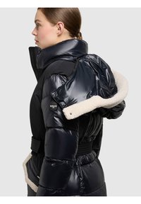 Gewatteerde zwarte pufferjas met een glanzende afwerking, voorzien van een afneembare crèmekleurige nepbontkraag, zijzakken en een taille met ceintuur.