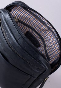 Black leather crossbody bag featuring multiple zip pockets, a checkered fabric lining, and a textured finish.