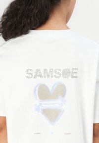 White cotton t-shirt featuring a graphic print with the word "SAMSØE" and a blue and beige heart design on the back.