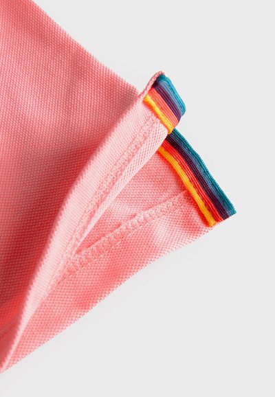 Roze stof met een gestructureerd oppervlak, met een meerkleurige gestreepte rand in turquoise, geel, paars en oranje aan de bovenkant.