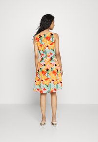 Vestido floral de verão apresenta flores vibrantes em laranja e rosa sobre um fundo verde menta, com uma cintura ajustada e saia rodada.