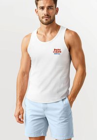 White tank top featuring red and blue text reading "Pasta La Vista Neverless." Worn with light blue shorts, showcasing a fitted design.