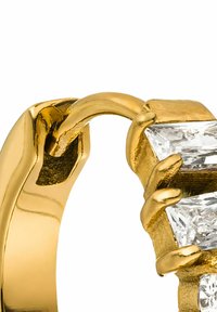 Goldene Creole mit einem klauenähnlichen Design, das einen klaren, funkelnden rechteckigen Stein hält. Glatte Metalloberfläche mit detaillierten Akzenten.