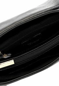 Interno di una borsa in finta pelle nera con una texture liscia, dotato di una tasca con zip e più scomparti foderati in tessuto nero.