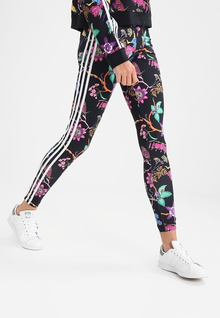 Svarta leggings med ett livligt blommönster i rosa, grönt och lila, med vita ränder längs sidorna och en figurnära design.
