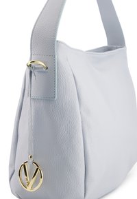 Hellblaues Lederhandtasche mit einer strukturierten Oberfläche, einem einzelnen Tragegurt und einem goldfarbenen Logo-Detail an der Seite. Minimalistisches Design.