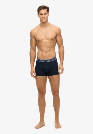 Boxers ajustados negros con una amplia cinta elástica azul en contraste que presenta el logo "SUPERDRY". Diseño ceñido y tejido suave.