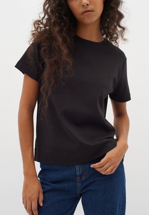 Sort, kortærmet t-shirt lavet af blødt stof med rund hals og afslappet pasform, parret med blå denim jeans.
