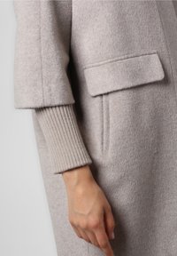 Cappotto in lana grigio chiaro con una texture morbida, dotato di un colletto a revers, tasche laterali e dettagli a costine sui polsini.