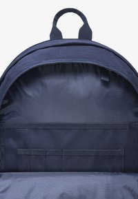 Mörkblå ryggsäck interiör med texturerat tyg, utrustad med ett huvudfack och flera horisontella nätfickor för organisering.