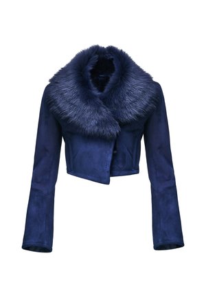Femme portant une veste bleu marine à col en fourrure et une robe noire fendue à la cuisse, tenant un sac à main en fourrure bleu marine assorti.
