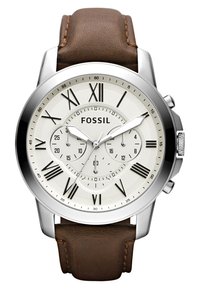 Montre en acier inoxydable argenté avec un cadran blanc, des chiffres romains, des sous-cadrans et un bracelet en cuir marron. Elle présente des accents polis et des détails texturés.
