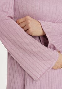 Jasnoróżowa bluzka z długim rękawem o pionowym prążkowanym wzorze, z rękawami w kształcie dzwonu o średniej długości i subtelnymi detalami szwów.