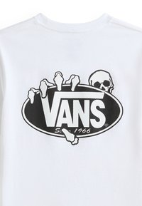 Camiseta blanca con logo negro de Vans que presenta manos esqueléticas y una calavera surgiendo alrededor del óvalo, texto "Since 1966" debajo del logo.