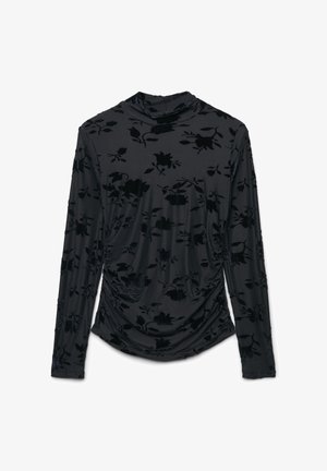 Haut noir à manches longues en tissu doux, présentant un motif floral en velours et un design drapé. Col haut et détails froncés sur les côtés.
