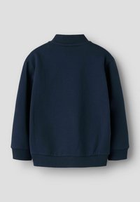 Tumši zils džemperis ar augstu apkakli, garām piedurknēm un ribotām aprocēm un apakšmalu. Mīksta tekstūra un minimālistisks dizains. Parādīta aizmugures skats.